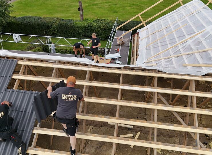 Vestjysk Mesterbyg medarbejder ved en af vores biler på en byggegrund, og et skilt med Vestjysk Mesterbyg.